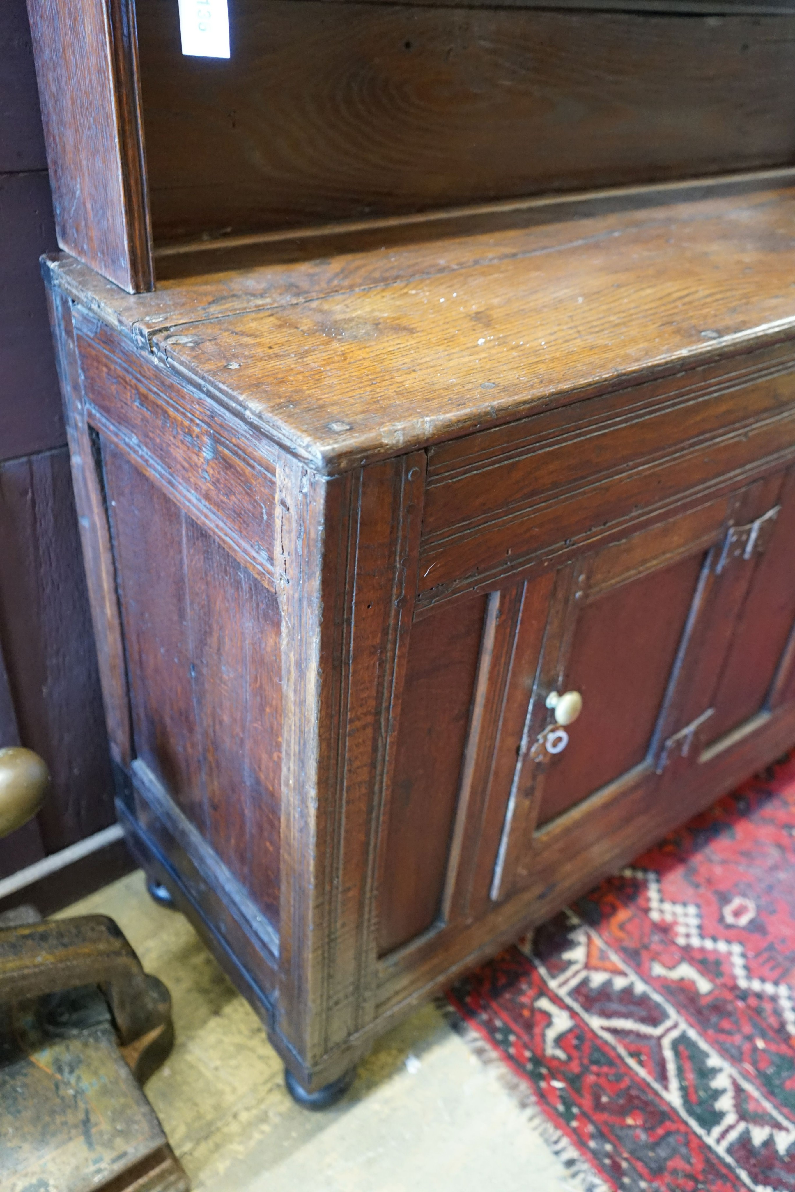 A 18th century and later small oak dresser with boarded rack, width 127cm depth 38cm height 166cm